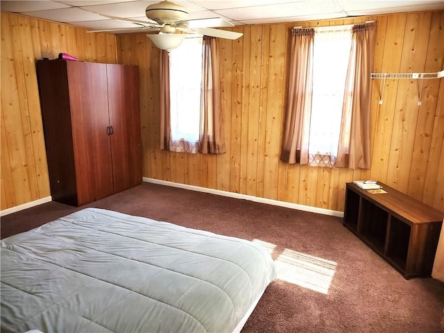 bedroom with carpet, baseboards, and wood walls