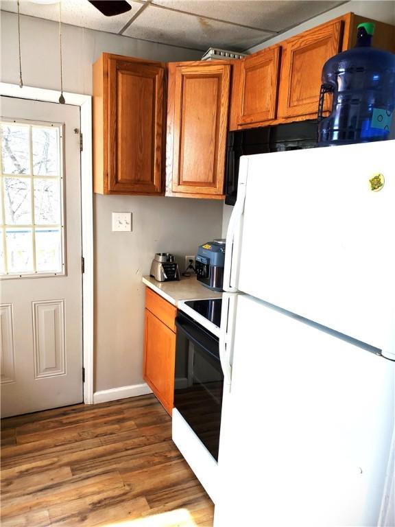 kitchen with light wood finished floors, range with electric stovetop, brown cabinetry, and freestanding refrigerator