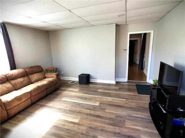 living area with baseboards, a paneled ceiling, visible vents, and wood finished floors