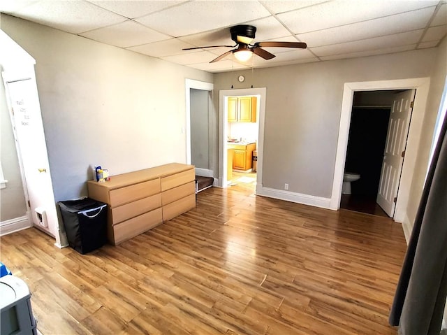 bedroom featuring ensuite bath, light wood finished floors, a paneled ceiling, baseboards, and ceiling fan