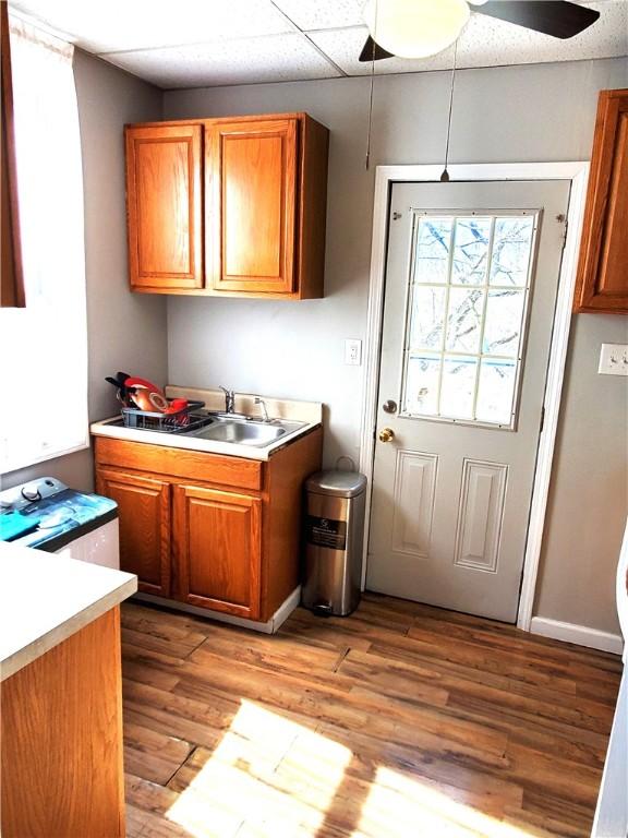 kitchen featuring a sink, brown cabinetry, a ceiling fan, and light countertops