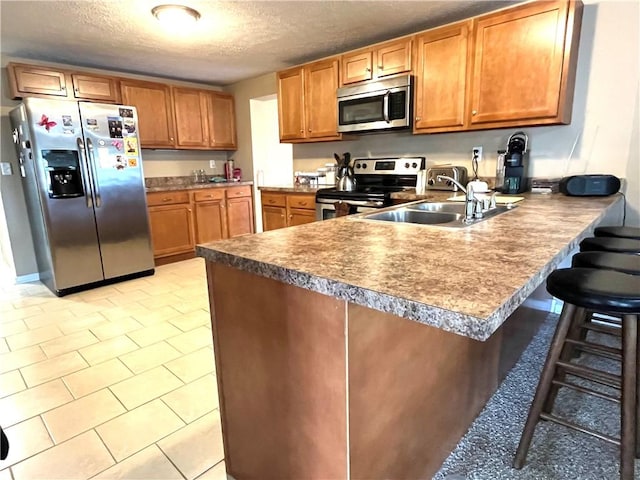 310 Church St, Harrisville Boro, PA 16038 - kitchen featuring stainless steel appliances, a textured ceiling, a peninsula, brown cabinets, and a breakfast bar