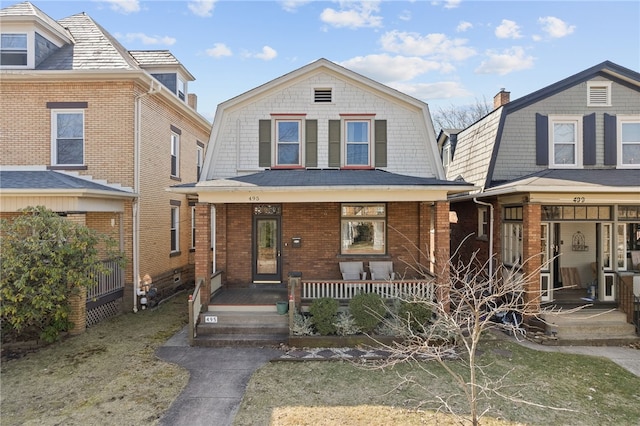 view of front of house with a gambrel roof, covered porch, and brick siding