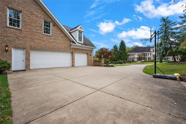view of side of home with brick siding, a yard, concrete driveway, and a garage