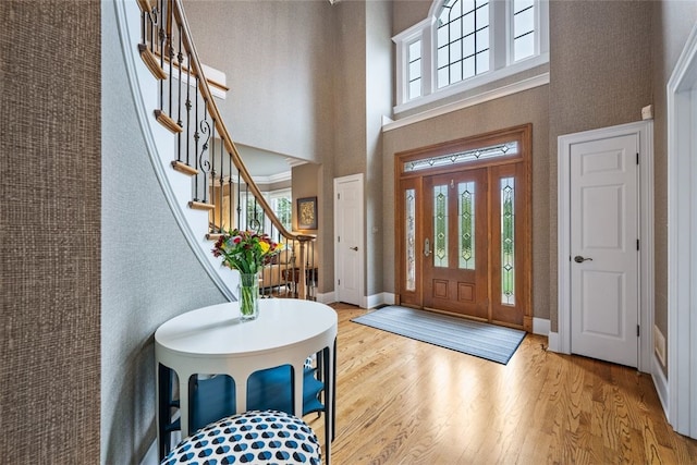 entryway featuring stairway, baseboards, a high ceiling, and wood finished floors