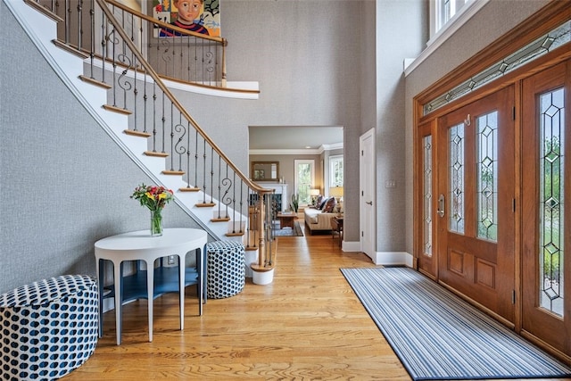 entrance foyer featuring wood finished floors, stairway, a high ceiling, crown molding, and baseboards