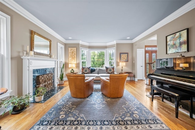 living room featuring baseboards, wood finished floors, a high end fireplace, and ornamental molding