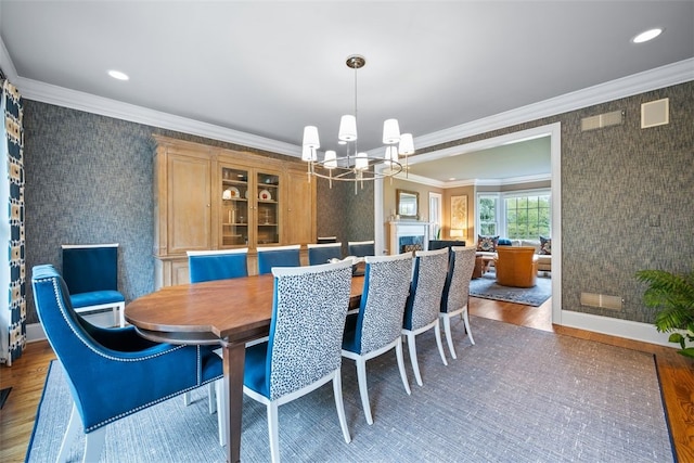 dining area featuring wallpapered walls, crown molding, a chandelier, recessed lighting, and wood finished floors