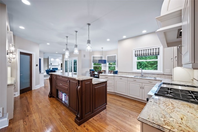 kitchen featuring dark brown cabinetry, recessed lighting, light wood-style floors, and a sink