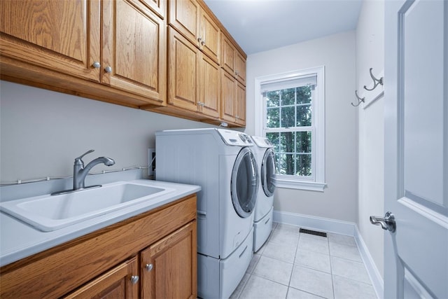 clothes washing area with visible vents, washing machine and clothes dryer, light tile patterned flooring, cabinet space, and a sink