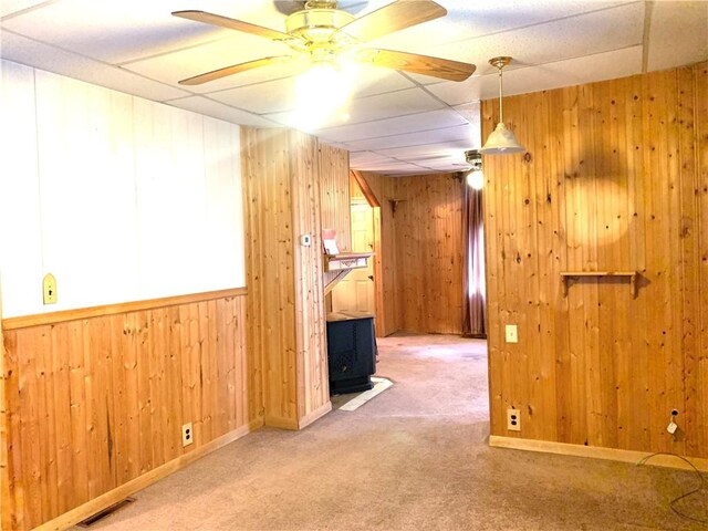 406 Peach St, City Of But Ne, PA 16001 - unfurnished room with carpet flooring, wooden walls, a wood stove, a ceiling fan, and a drop ceiling
