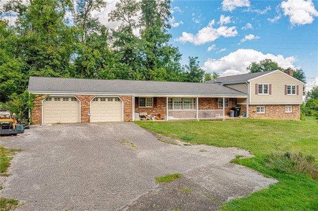 split level home with aphalt driveway, brick siding, a garage, and a front yard
