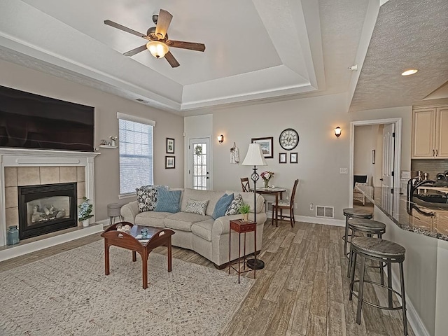 232 Adams Pointe Blvd Unit 6, Adams Twp, PA 16046 - living area featuring light wood-style floors, a tray ceiling, ceiling fan, baseboards, and a fireplace