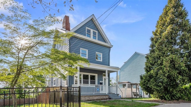 american foursquare style home with covered porch, a chimney, and fence private yard