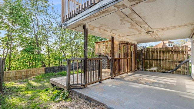 wooden terrace featuring a fenced backyard and a carport