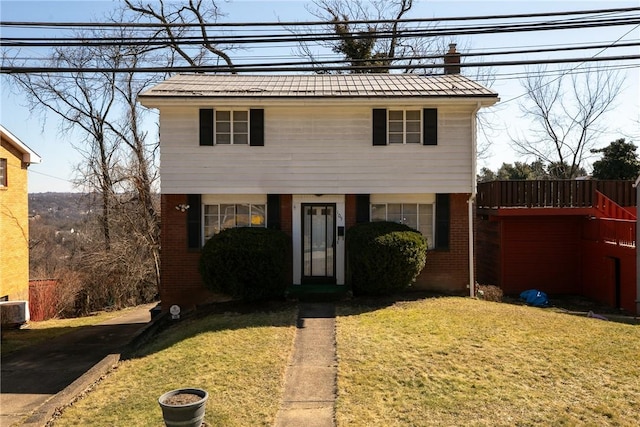 colonial inspired home with a front yard and brick siding