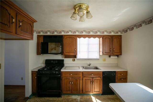kitchen featuring black appliances, light countertops, brown cabinets, and a sink