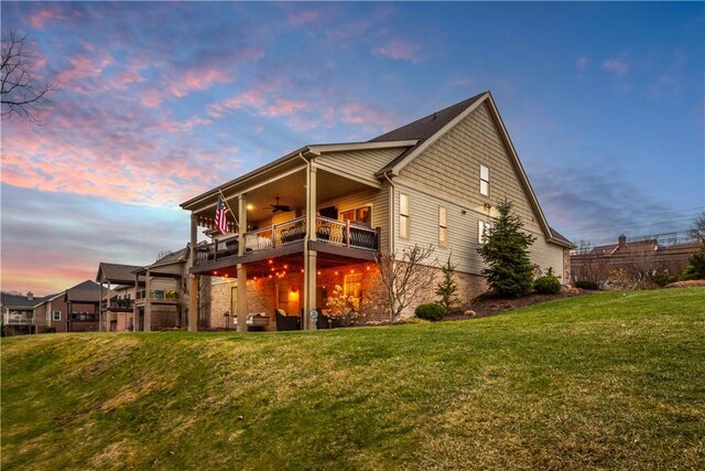 back of house featuring a yard, a balcony, and a ceiling fan