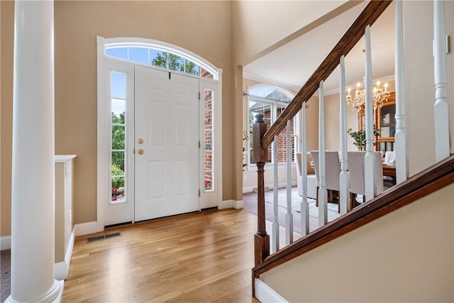 entrance foyer featuring visible vents, a notable chandelier, stairway, light wood finished floors, and baseboards