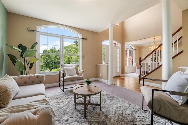 living room featuring an inviting chandelier, carpet flooring, decorative columns, baseboards, and stairs