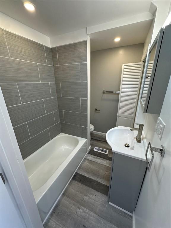 bathroom featuring vanity, toilet, recessed lighting, baseboards, and wood finished floors