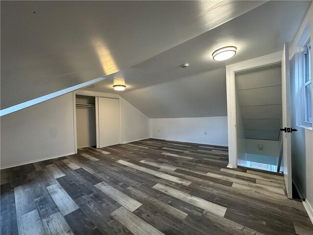 additional living space with baseboards, vaulted ceiling, and dark wood-style flooring