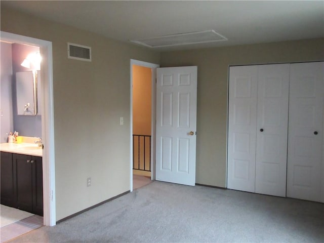 unfurnished bedroom with visible vents, light carpet, a sink, a closet, and attic access