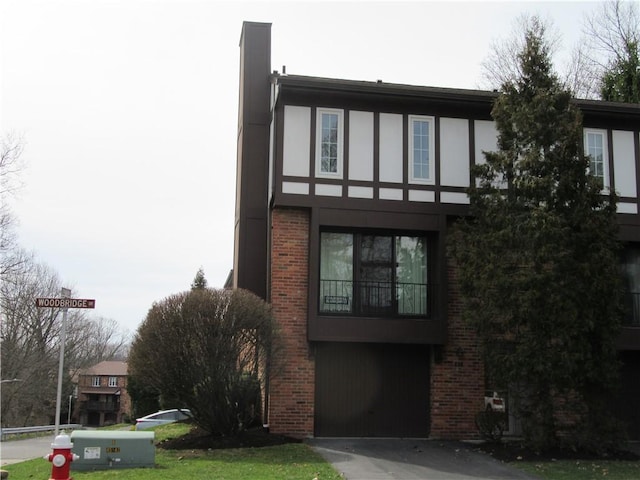 view of front of home featuring aphalt driveway, brick siding, an attached garage, and stucco siding