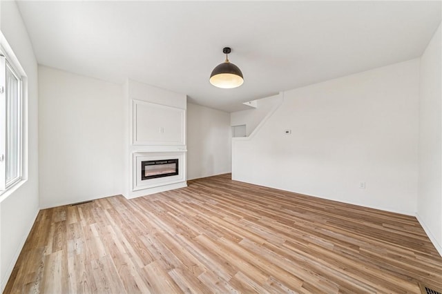 5021 Broad St, Garfield, PA 15224 - unfurnished living room with light wood-type flooring and a glass covered fireplace