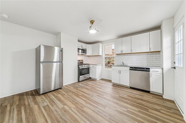 5021 Broad St, Garfield, PA 15224 - kitchen with stainless steel appliances, light wood-style floors, tasteful backsplash, and white cabinets