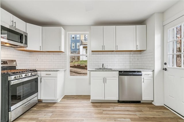 5021 Broad St, Garfield, PA 15224 - kitchen with stainless steel appliances, light wood-style flooring, light stone countertops, and white cabinetry