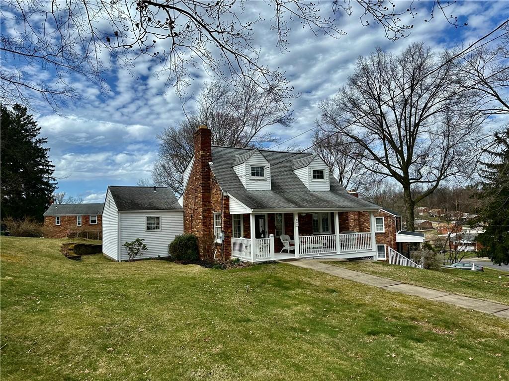 exterior space featuring a porch, a yard, and a chimney