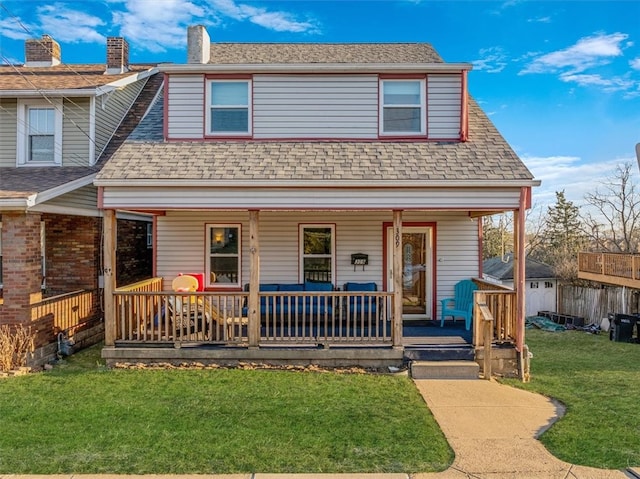 view of front of house with covered porch, a front yard, and a shingled roof