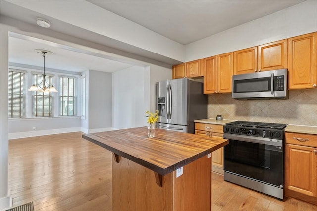 kitchen featuring appliances with stainless steel finishes, wood counters, a chandelier, backsplash, and light wood-style floors