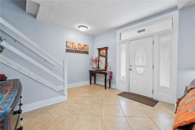foyer entrance with stairway, light tile patterned floors, and baseboards