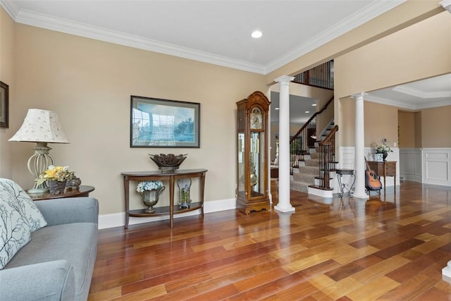 foyer entrance with stairway, wood finished floors, ornate columns, wainscoting, and crown molding