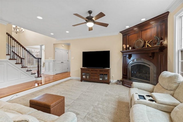 living room featuring ceiling fan, stairway, ornamental molding, light carpet, and a fireplace