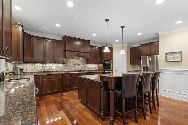 kitchen with a kitchen island, dark wood finished floors, custom exhaust hood, gas cooktop, and a sink