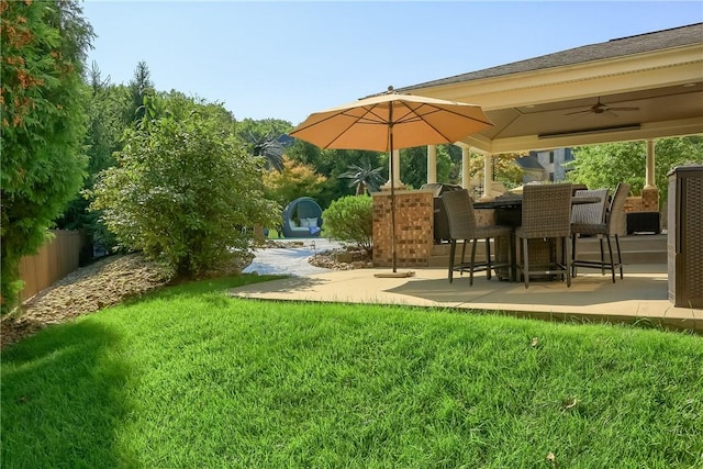 view of yard featuring fence, ceiling fan, and a patio area