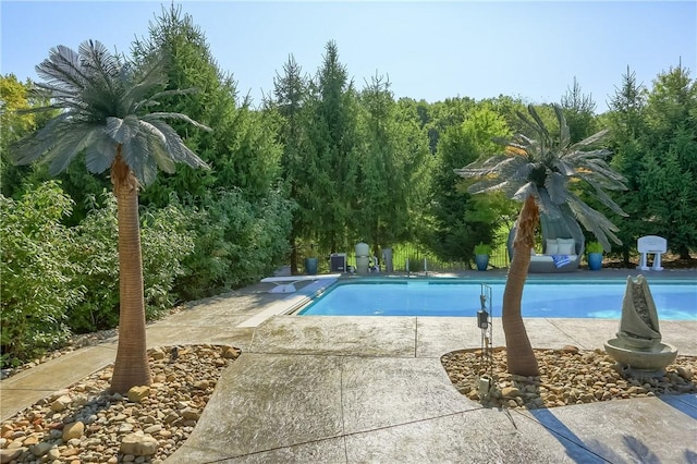 outdoor pool with a diving board and a patio