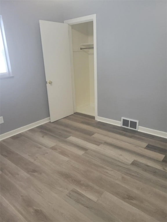 unfurnished bedroom with visible vents, baseboards, a closet, and wood finished floors