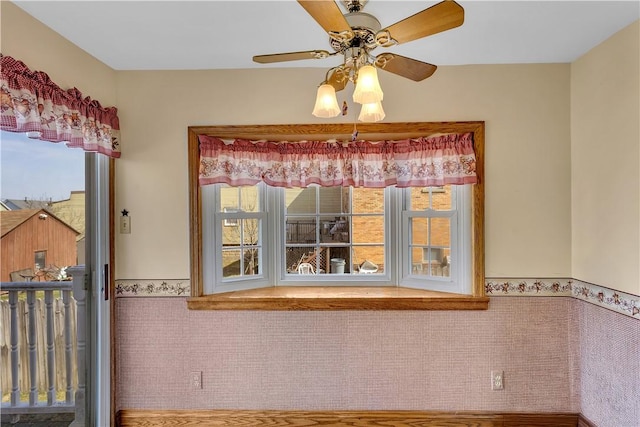 unfurnished dining area featuring ceiling fan, tile walls, and wainscoting
