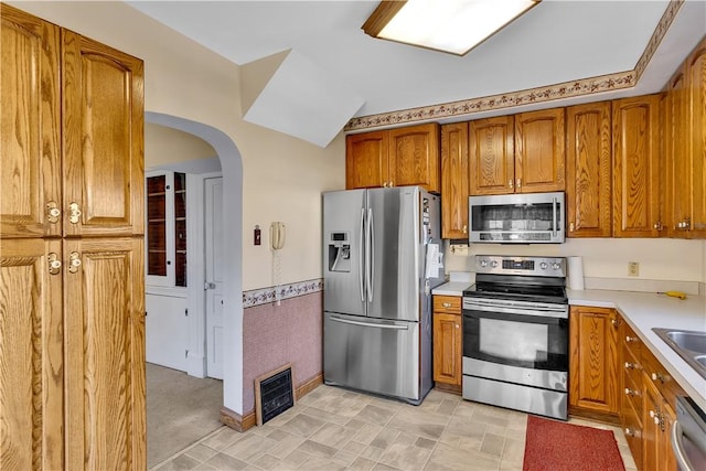 kitchen featuring a wainscoted wall, visible vents, appliances with stainless steel finishes, and brown cabinets