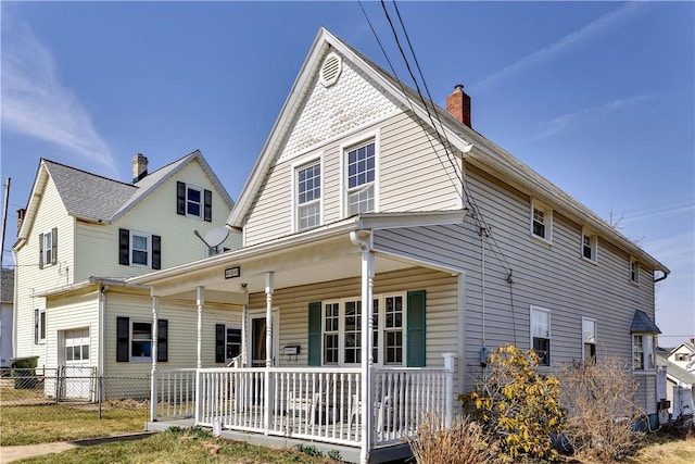 view of front of house featuring a porch, a chimney, and fence