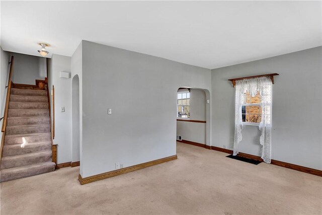 empty room with stairway, arched walkways, and carpet floors