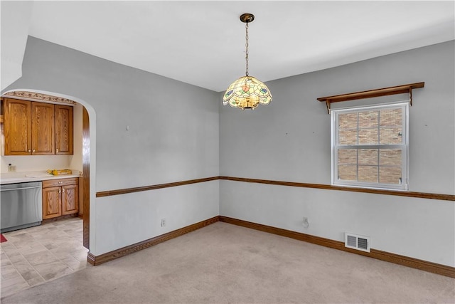 unfurnished dining area with arched walkways, visible vents, light colored carpet, and baseboards
