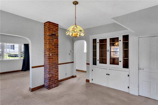 carpeted empty room with baseboards and arched walkways