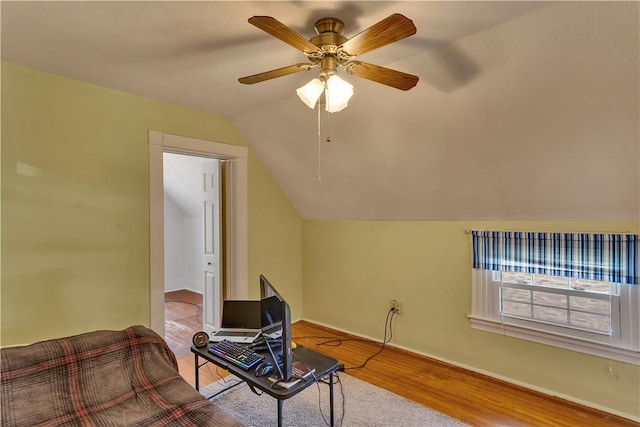 interior space with ceiling fan, baseboards, lofted ceiling, and wood finished floors