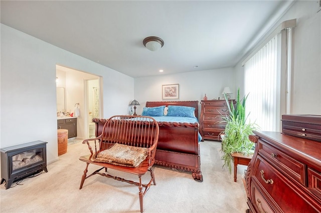 bedroom with light carpet, ensuite bath, and a wood stove