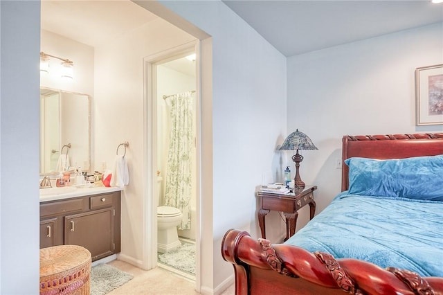 bedroom with connected bathroom, light colored carpet, and baseboards